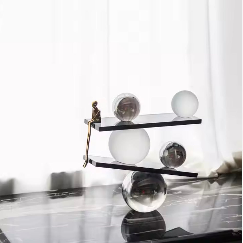 Abstract balancing sculpture with chrome spheres and a small gold figurine