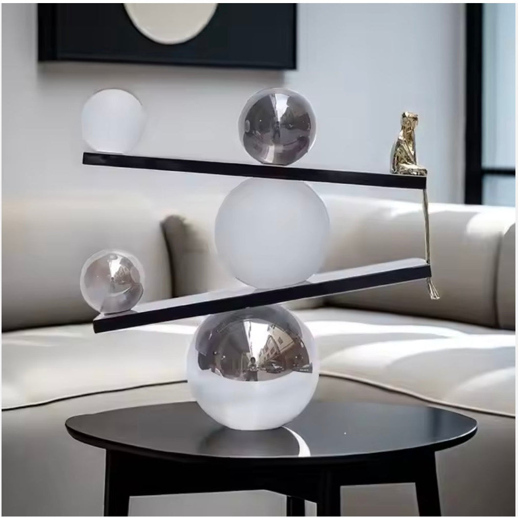 Abstract balancing sculpture with chrome spheres and a small gold figurine