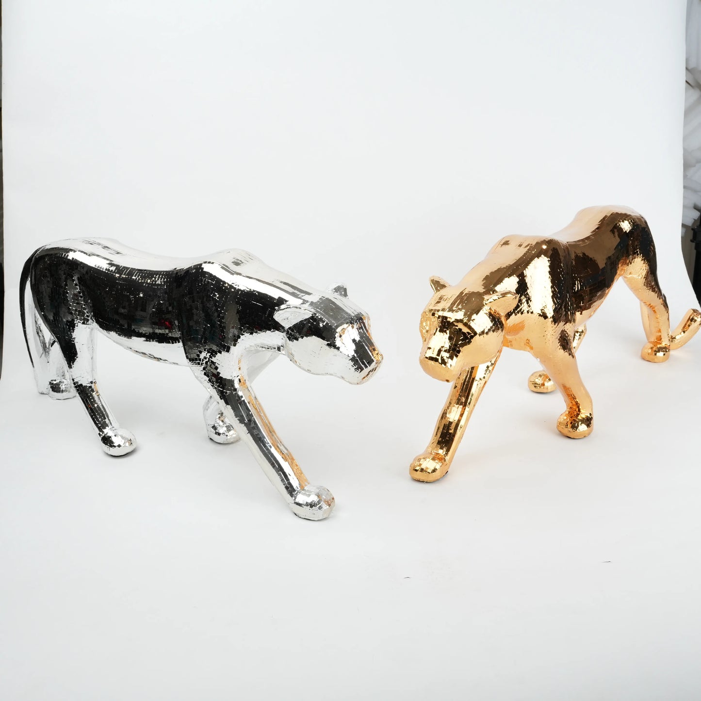 Metallic panther figurines in gold and silver on a white background