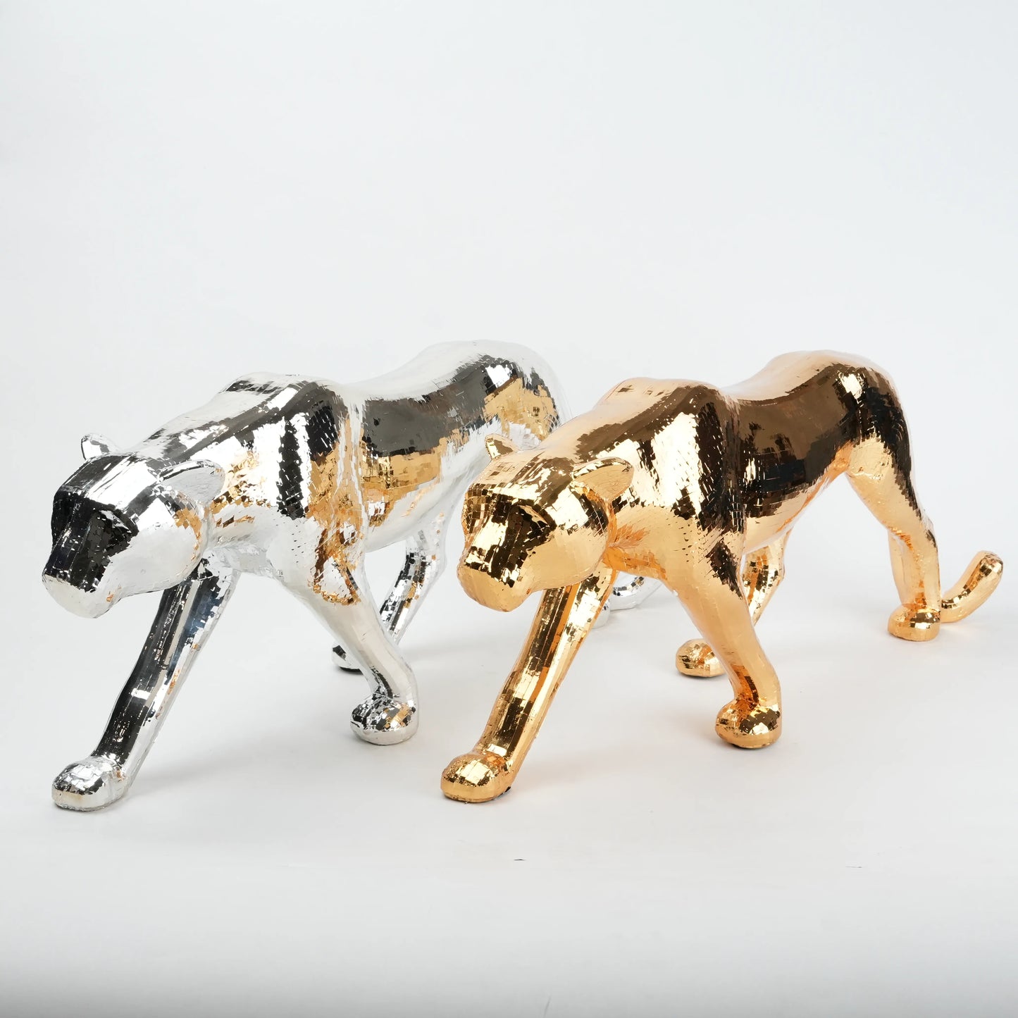 Gold and silver panther figurines on a white background