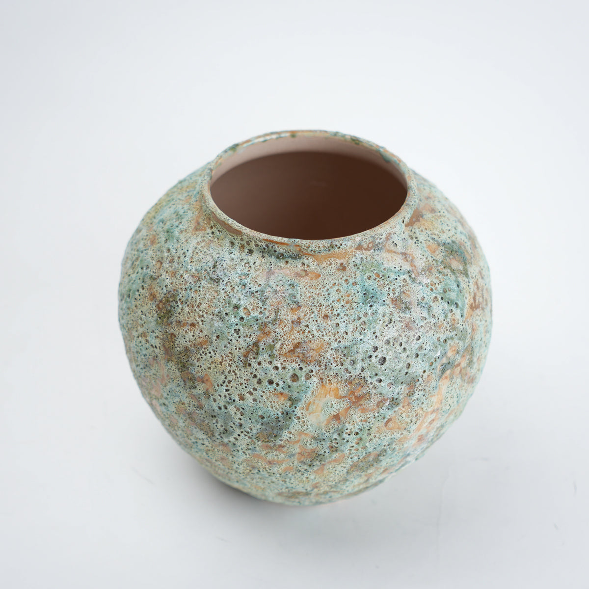 Round ceramic pot with textured surface on a white background