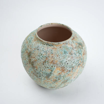 Round ceramic pot with textured surface on a white background