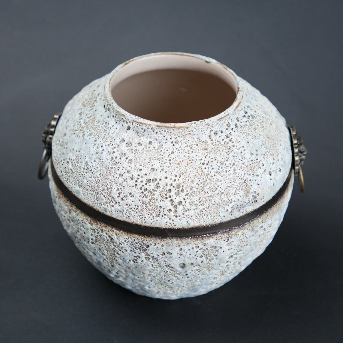 Textured ceramic vase with decorative bands on a dark background