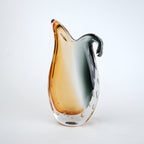 Glass pitcher with gradient color from orange to clear on a white background