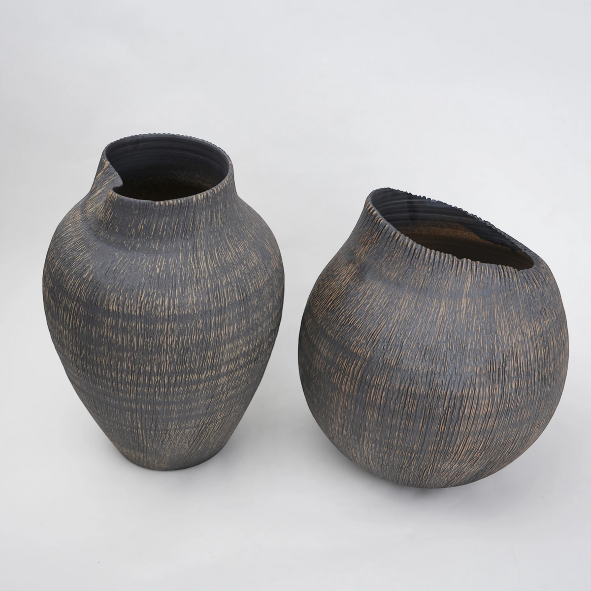 Two dark brown ceramic vases on a light gray background