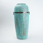 Turquoise ceramic urn with decorative patterns on a white background