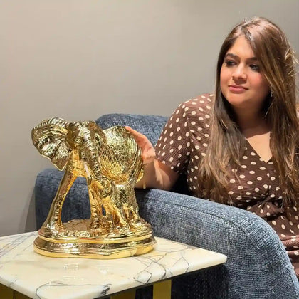 Woman holding a gold elephant statue on a marble surface