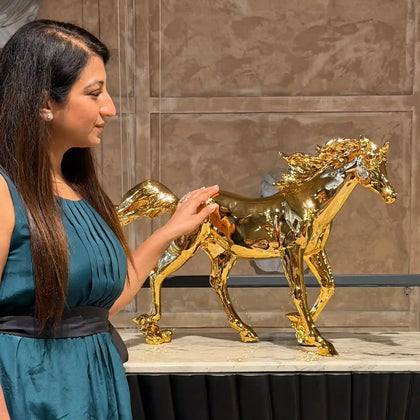Woman interacting with a gold horse sculpture placed on a console table