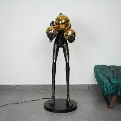 Modern black and gold sculpture on a gray floor with a white wall background