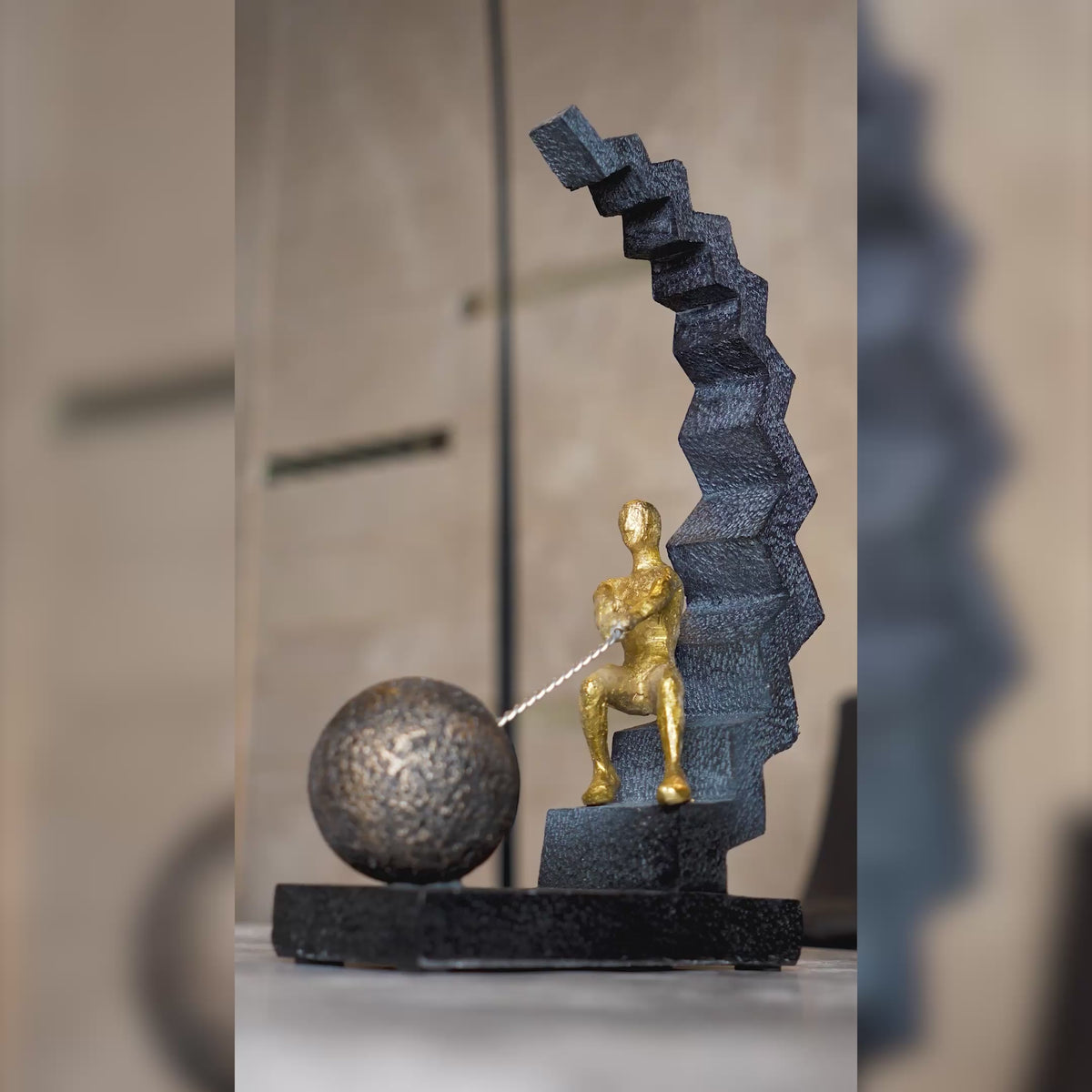 Modern abstract human figure decor seated on geometric staircase pulling a sphere, black and gold tabletop accent for living room, office desk or console styling
