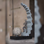 Abstract human figure decor seated on geometric staircase holding chain with sphere, modern tabletop accent for living room, office desk or console styling