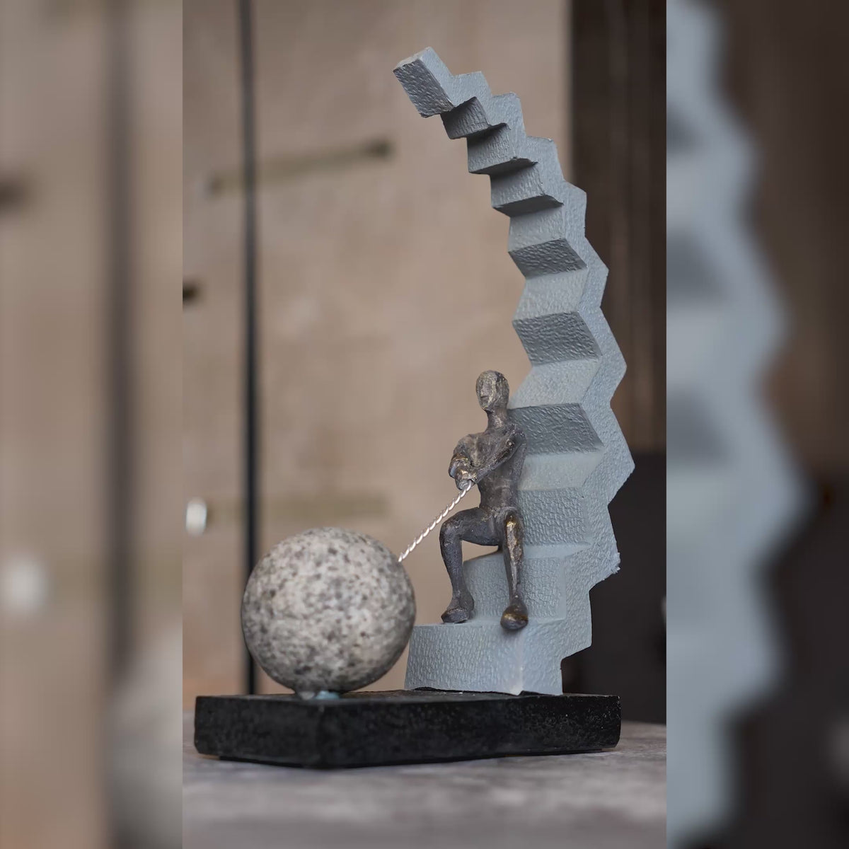 Abstract human figure decor seated on geometric staircase holding chain with sphere, modern tabletop accent for living room, office desk or console styling