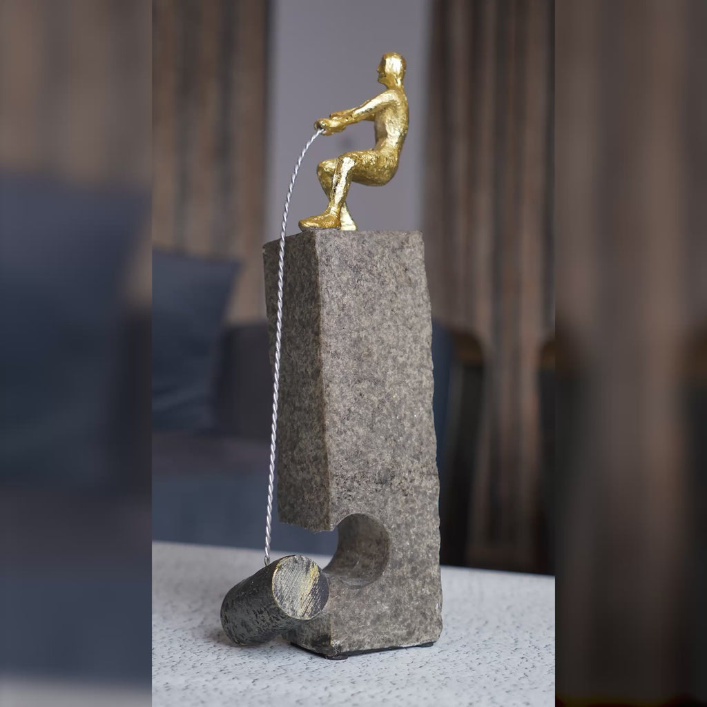 Modern abstract human figure table accent with gold detailing mounted on a textured stone base displayed in a luxury interior setting