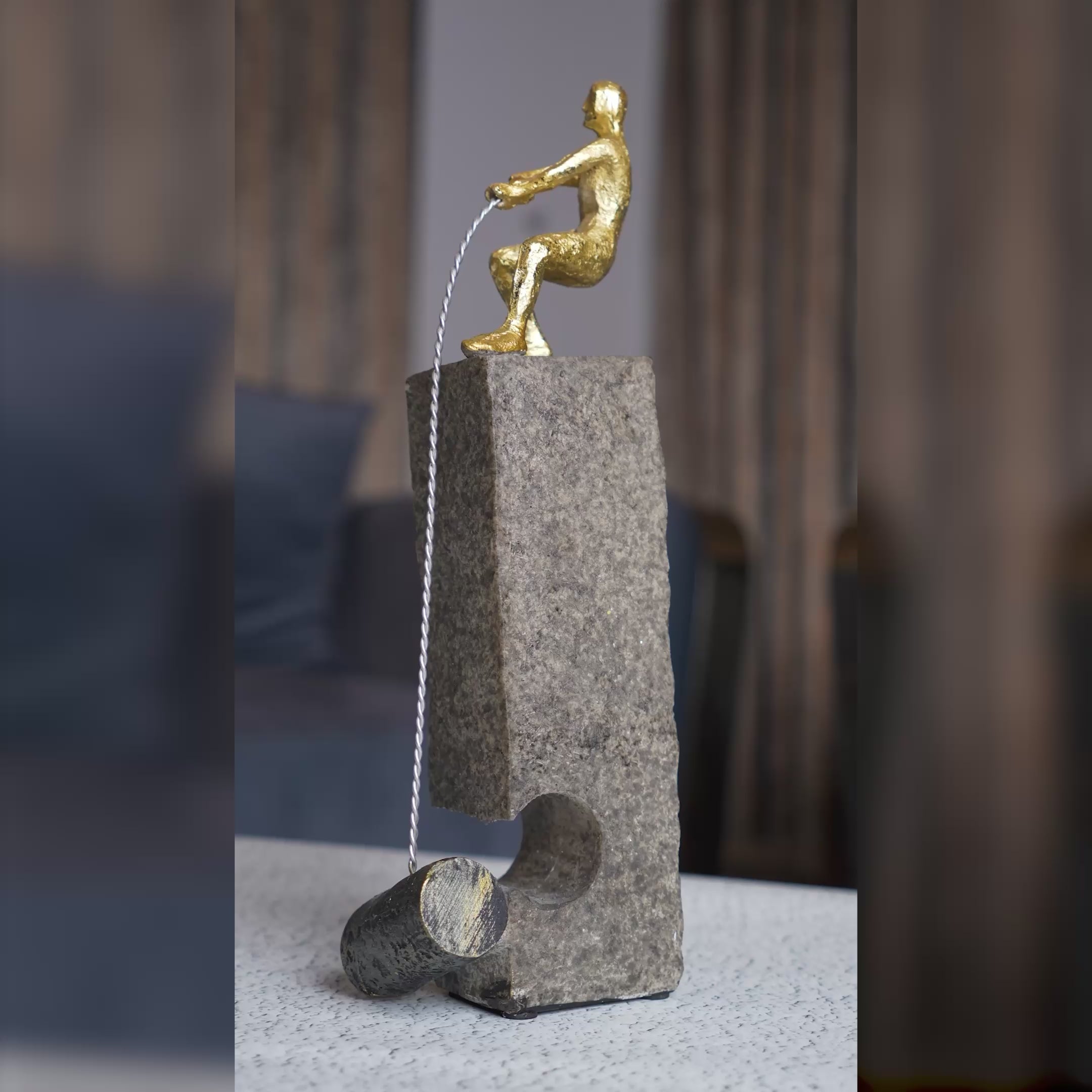 Modern abstract human figure table accent with gold detailing mounted on a textured stone base displayed in a luxury interior setting