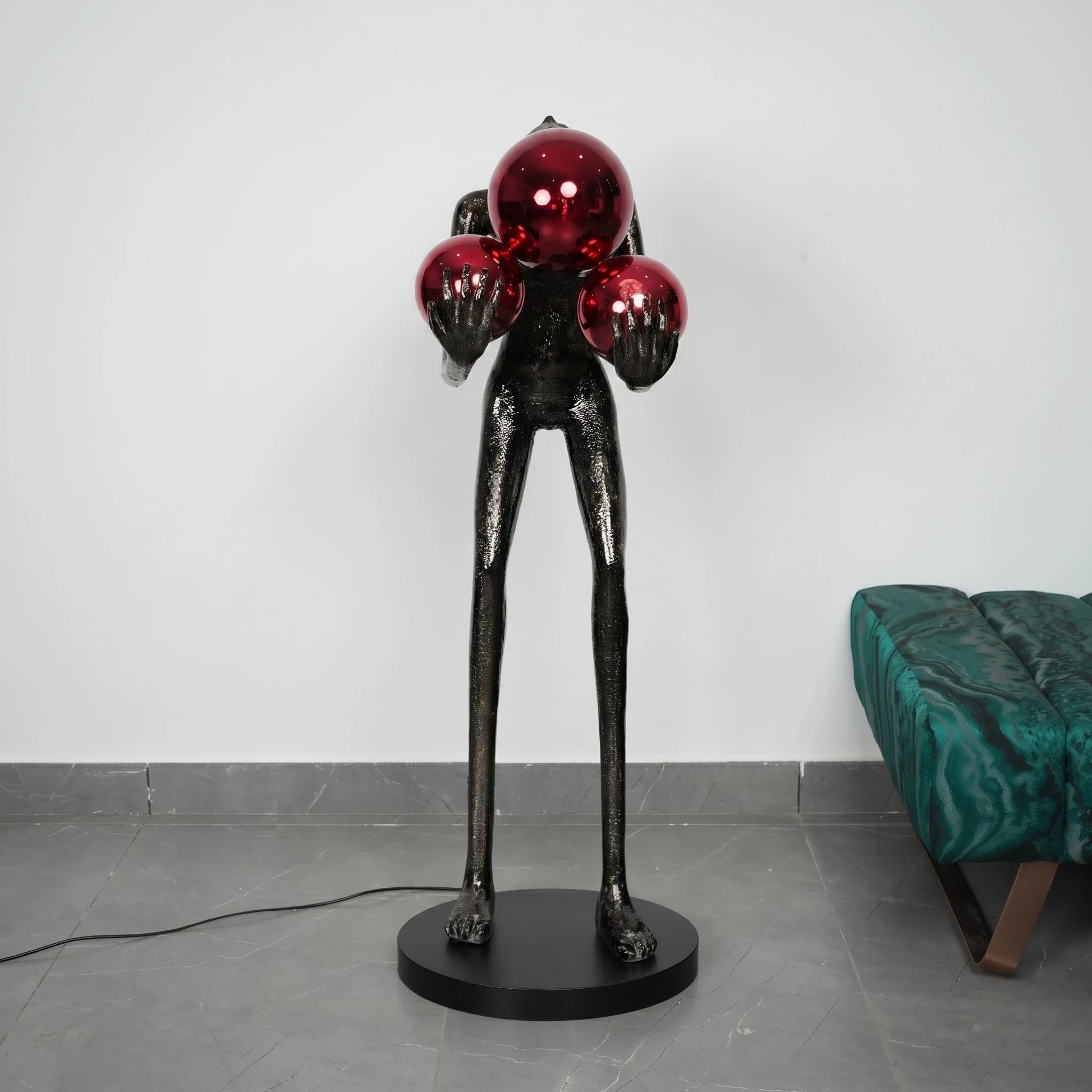 Sculpture with red spherical objects on a black base against a white wall.